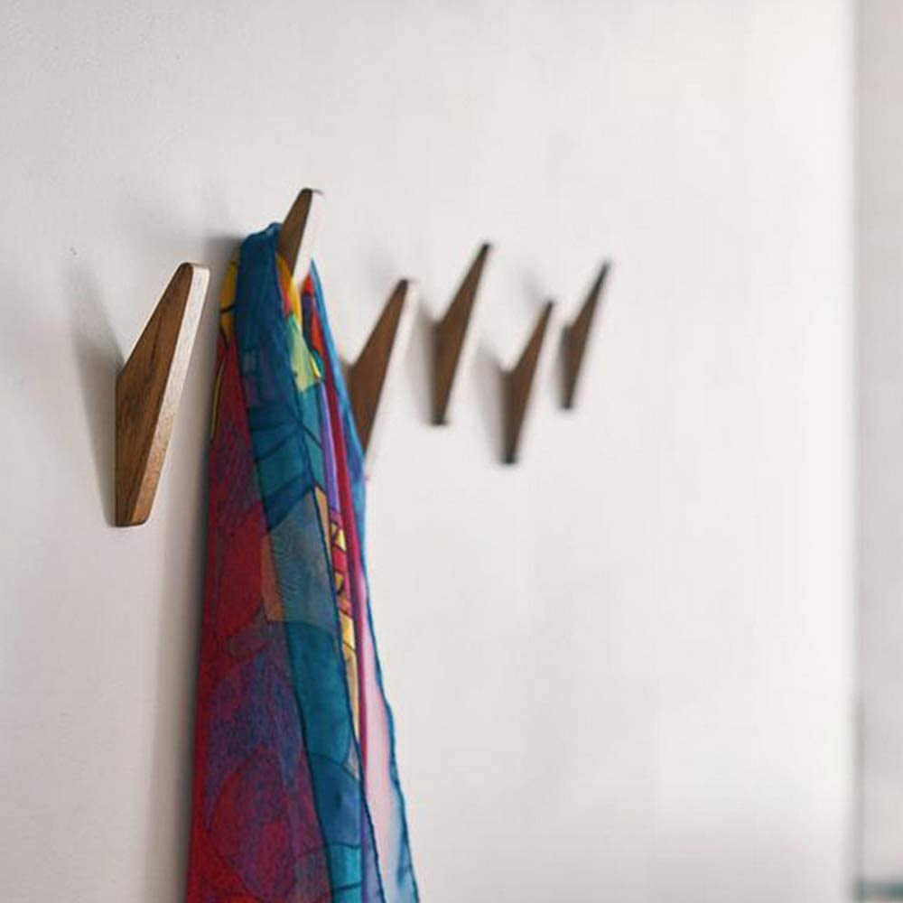 Braune Holzhaken als Detail an einer Wand mit einem bunt gemusterten Tuch.