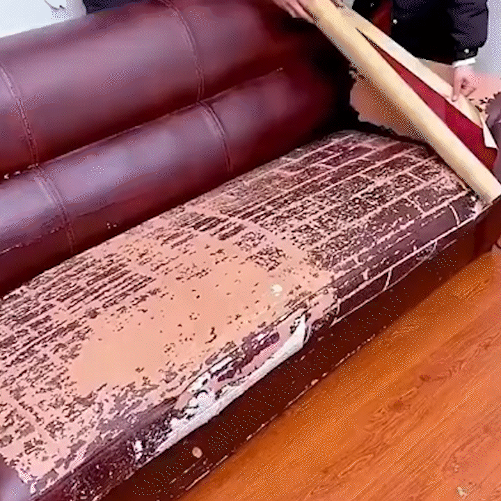 Abgenutzte, abgeplatzte Sitzfläche eines bordeauxroten Ledersofas, während jemand eine Bahn des Flickens darüber abrollt. 22