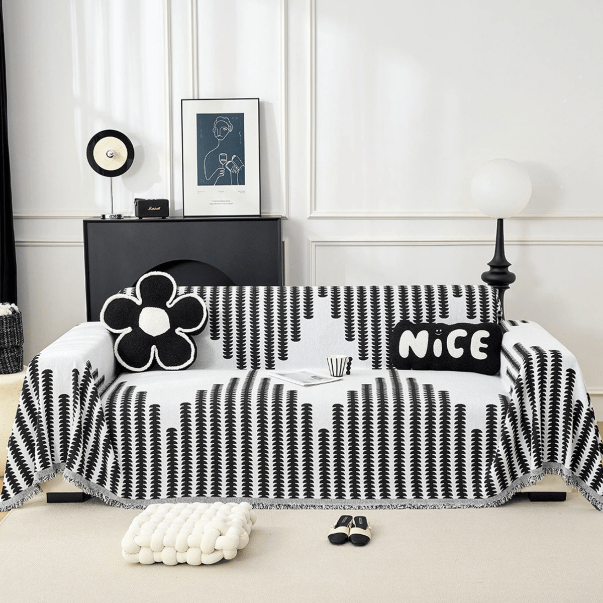 Schwarz-weißer Sofabezug mit grafischem Muster und Fransenrand auf einem Sofa