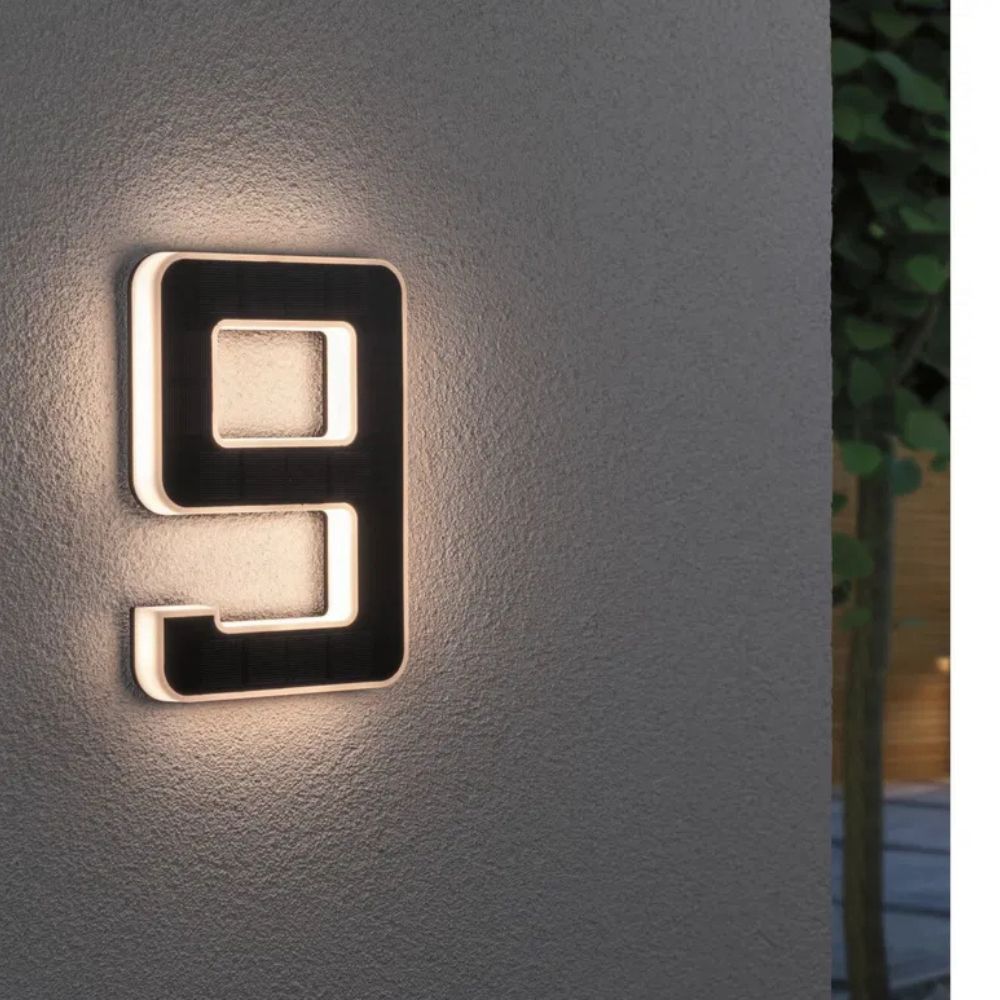 Solarbeleuchtete Hausnummer mit Ziffer 9 in Schwarz und Weiß an einer grauen Wand