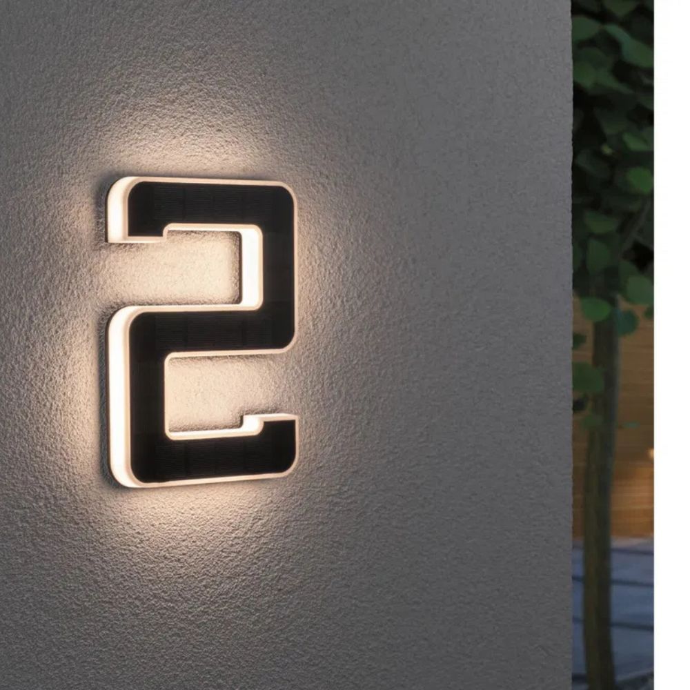 Solarbeleuchtete Hausnummer mit Ziffer 2 in Schwarz und Weiß an einer grauen Wand