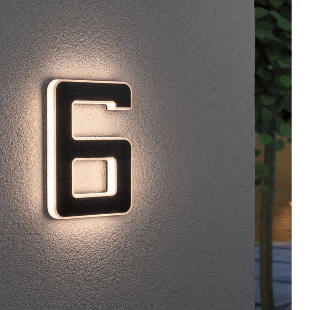 Solarbeleuchtete Hausnummer mit Ziffer 6 in Schwarz und Weiß an einer grauen Wand
