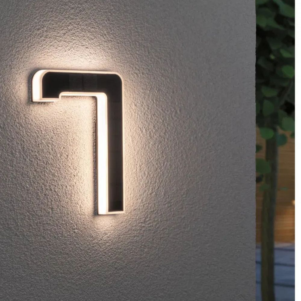 Solarbeleuchtete Hausnummer mit Ziffer 7 in Schwarz und Weiß an einer grauen Wand