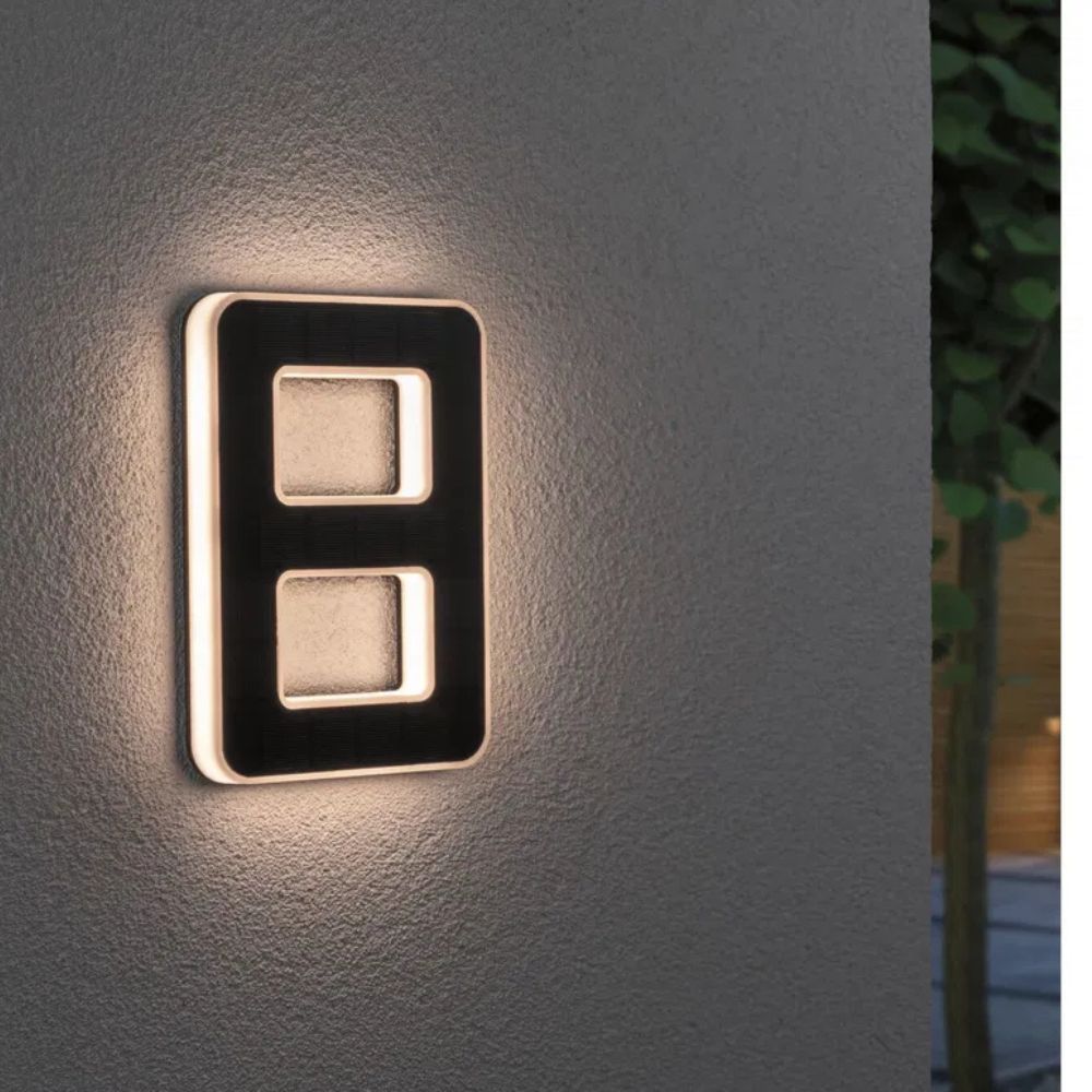 Solarbeleuchtete Hausnummer mit Ziffer 8 in Schwarz und Weiß an einer grauen Wand