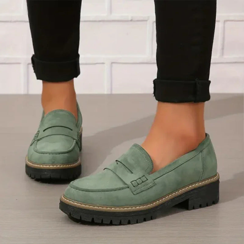 Grüne Loafer aus Leder mit Plateausohle, getragen zu schwarzen Hosen.