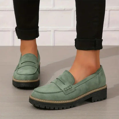 Grüne Loafer aus Leder mit Plateausohle, getragen zu schwarzen Hosen.