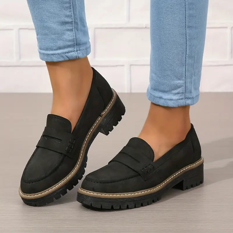 Schwarze Loafer mit kräftiger Profilsohle und heller Ziernaht.