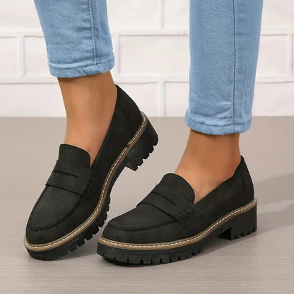 Schwarze Loafer mit kräftiger Profilsohle und heller Ziernaht.