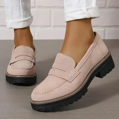 Zartrosa Loafer mit schwarzer Profilsohle, getragen zu weißen Hosen.