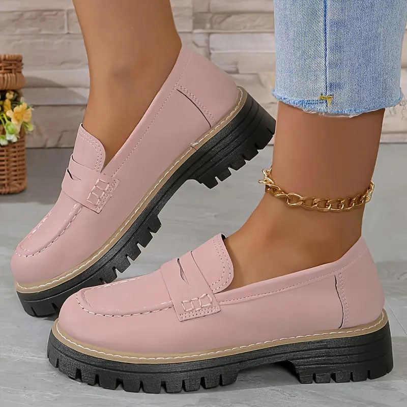 Rosa Loafer aus Leder mit Plateausohle, getragen mit goldener Fußkette.