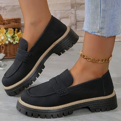 Schwarze Loafer mit heller Ziernaht an der Sohle und goldener Fußkette.