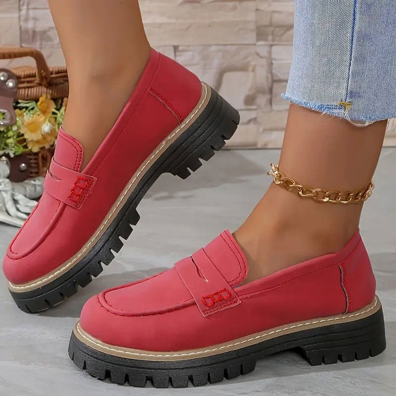 Rote Loafer mit roter Zierstichung am Riemen und dicker schwarzer Sohle.
