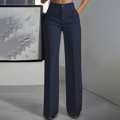 Dunkelblaue Hochtaillenhose mit Bügelfalte und geradem Bein, frontal vor grauer Wand mit Kunstwerk.