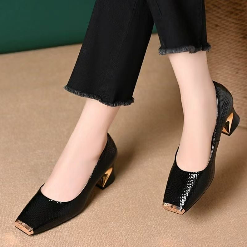 Schwarze Lackpumps mit Schlangenprägung und gewinkeltem Absatz, getragen mit schwarzer Jeans mit Fransensaum.
