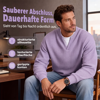 Mann im fliederfarbenen Waffelstrick-Oberteil sitzt nachdenklich auf einem Holzstuhl im Büro, Armbanduhr am Handgelenk, Stadtblick im Hintergrund. 6