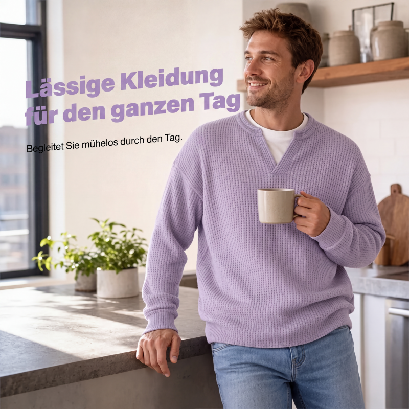 Lächelnder Mann im fliederfarbenen Waffelstrick-Oberteil hält in einer hellen Küche eine Tasse und lehnt an der Arbeitsplatte. 5