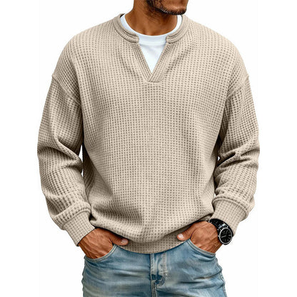 Frontansicht des Waffelstrick-Oberteils in Beige mit V-Ausschnitt und weißem Shirt darunter, getragen mit Jeans. 11