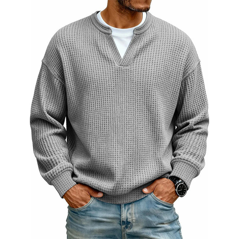 Frontansicht des Waffelstrick-Oberteils in Mittelgrau mit V-Ausschnitt und weißem Shirt darunter, getragen mit Jeans. 17