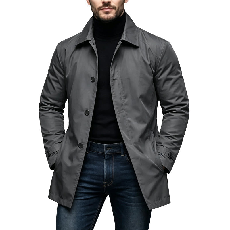 Mann trägt den Trenchcoat in Grau, offen über schwarzem Rollkragenpullover und Jeans, Hände in den Taschen 1