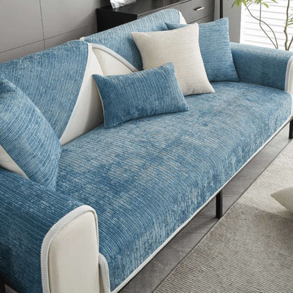 Blauer gerippter Sofaschutz auf einem Sofa mit blauen und beigen Kissen.
