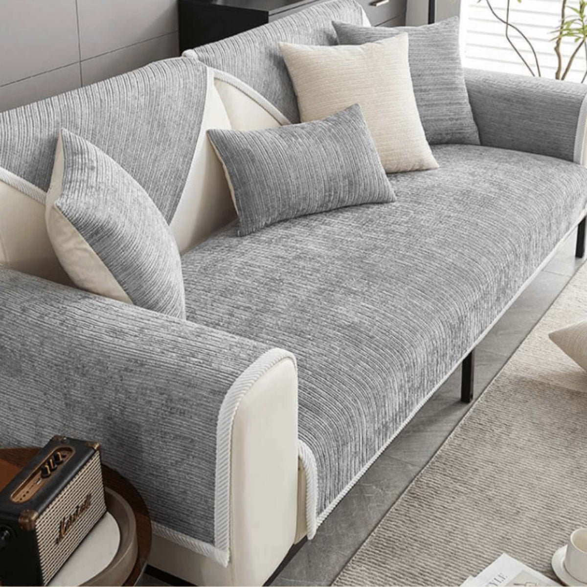 Grauer gerippter Sofaschutz auf einem Sofa mit grauen und beige Kissen.