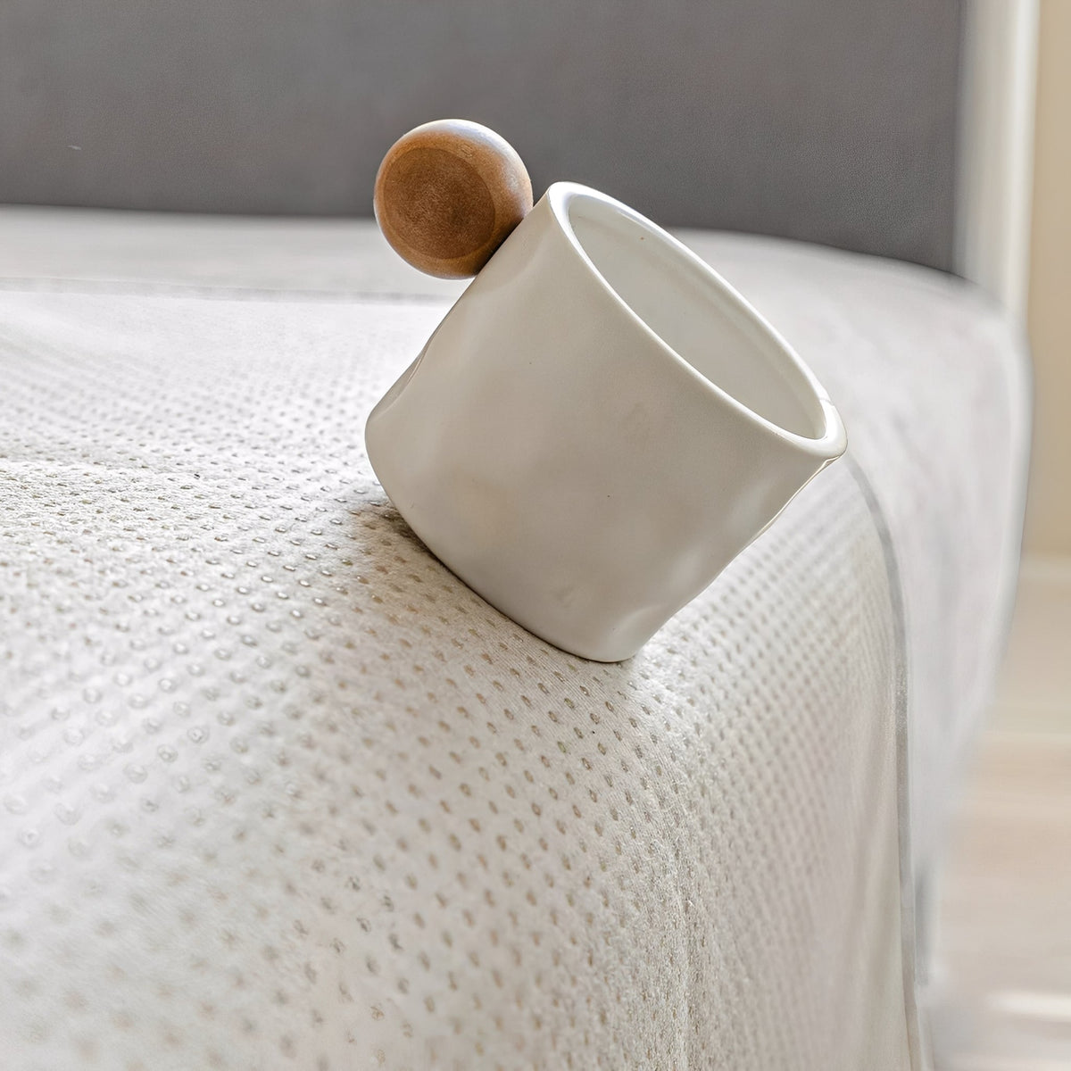Weiße Tasse mit Holzkugel auf der Ecke eines Sofas mit rutschhemmender Noppenrückseite.