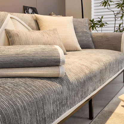 Beige-grauer Sofaschutz auf dem Sofa mit zwei gefalteten Stoffbahnen.