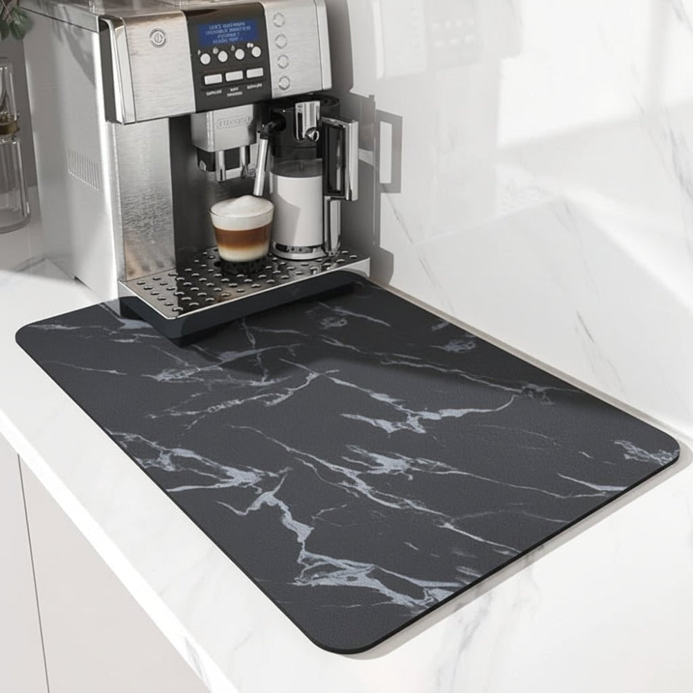 Schwarze Unterlage mit weißer Marmormaserung unter einem Kaffeevollautomaten, Blick von der Seite auf Glas und Milchbehälter. 4