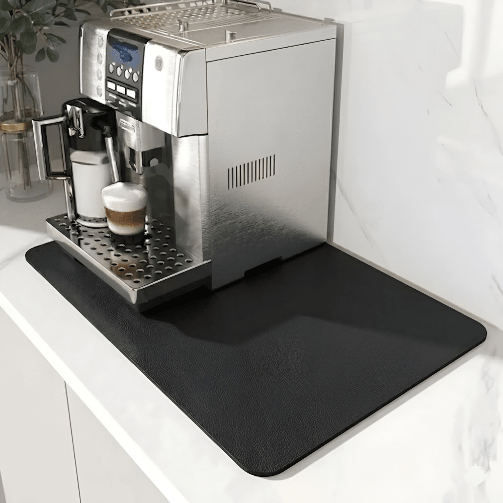 Schwarze Unterlage mit leicht genarbter Oberfläche unter einem Kaffeevollautomaten auf heller Marmor-Arbeitsplatte. 9