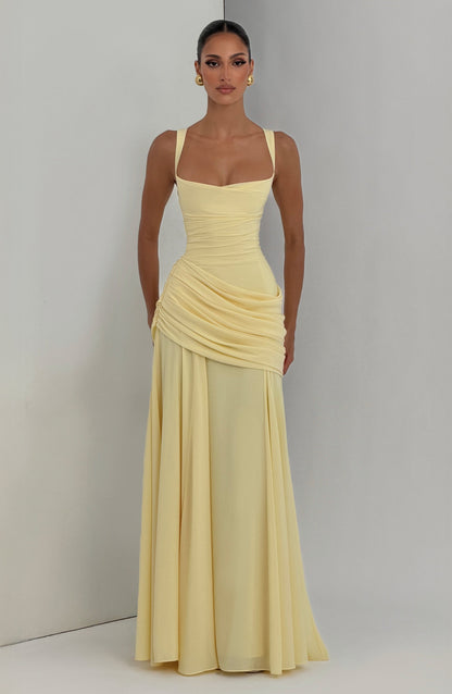 Das hellgelbe Maxikleid am Model vor hellgrauer Studiowand, frontal fotografiert.