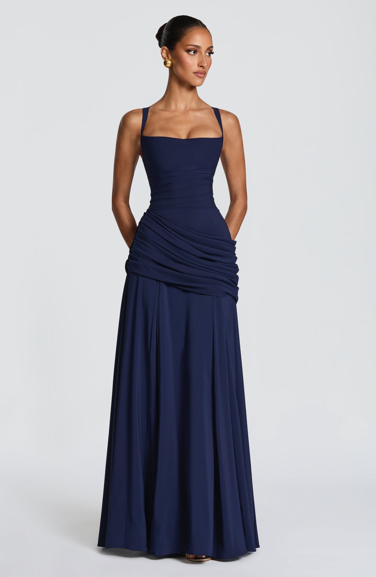 Marineblaues Maxikleid frontal am Model mit den Händen in den Seitentaschen.