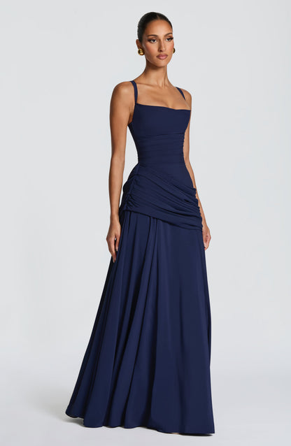 Marineblaues Maxikleid in Seitenansicht am Model mit seitlichem Drapé und weit schwingendem Rock.