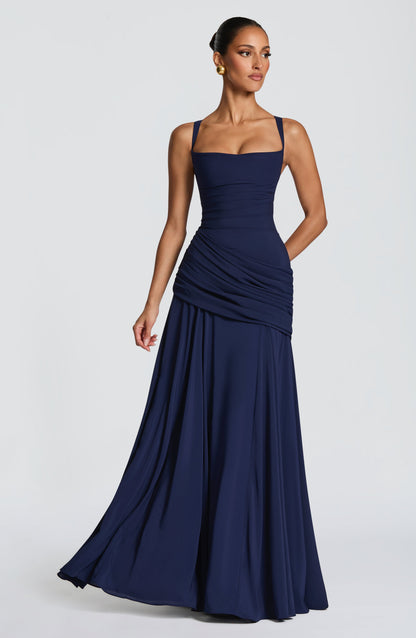 Das marineblaue Maxikleid in leicht seitlicher Pose, der weite Chiffonrock schwingt, das Drapé an der Hüfte liegt in Falten. 6