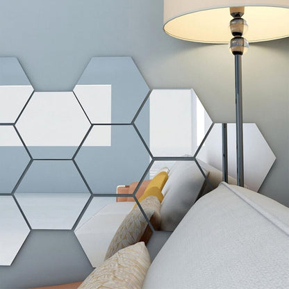 Sechseckige Spiegelaufkleber an einer blaugrauen Wand neben einer Stehlampe, im Spiegelbild sind Sofa und Kissen zu sehen. 6