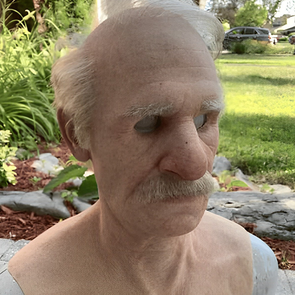 Realistische Maske eines älteren Mannes mit grauem Haar und Schnurrbart, im Garten schräg von der Seite fotografiert, Büste mit Schulterpartie. 21