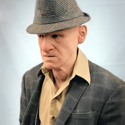 Realistische Gesichtsmaske eines älteren Mannes in Beige, Braun, Grau und Weiß, getragen, Seitenansicht.