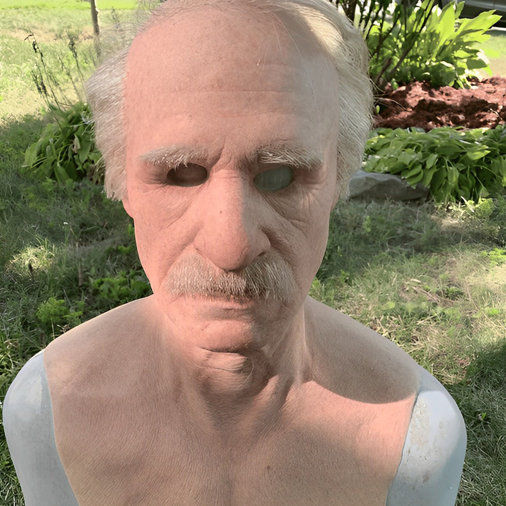 Realistische Gesichtsmaske eines älteren Mannes in Beige, Braun, Grau und Weiß, auf einer Büste im Freien.