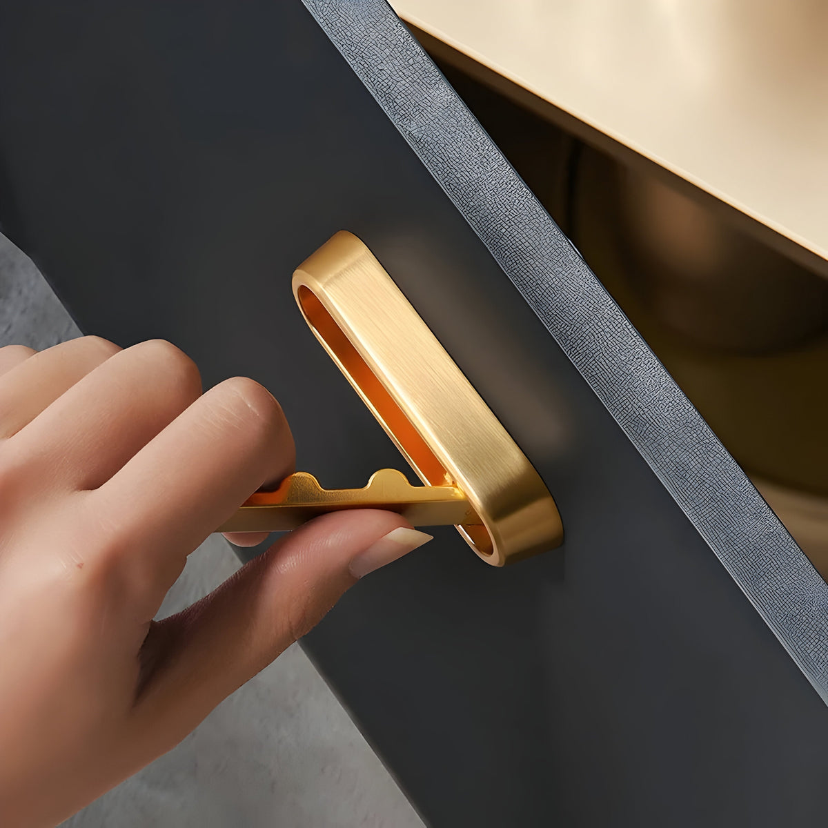 Hand klappt einen goldenen ovalen Haken aus einer dunklen Fläche heraus, Nahaufnahme der Bedienung.