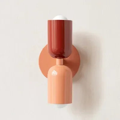 Einzelansicht der Wandlampe mit rotem Oberteil, pfirsichfarbenem Unterteil und lachsfarbenem Wandteller vor heller Wand. 20