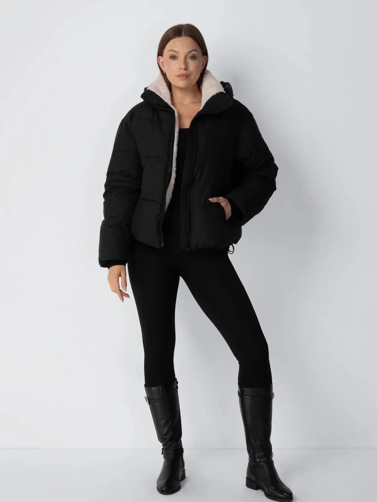Ganzkörperansicht der schwarzen Steppjacke mit schwarzen Leggings und hohen schwarzen Lederstiefeln 13