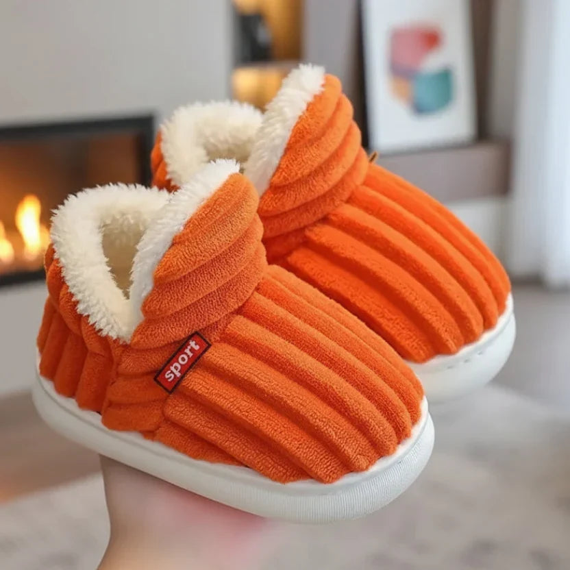 Orange gerippte Hausschuhe mit weißem Fleecefutter, in der Hand gehalten.