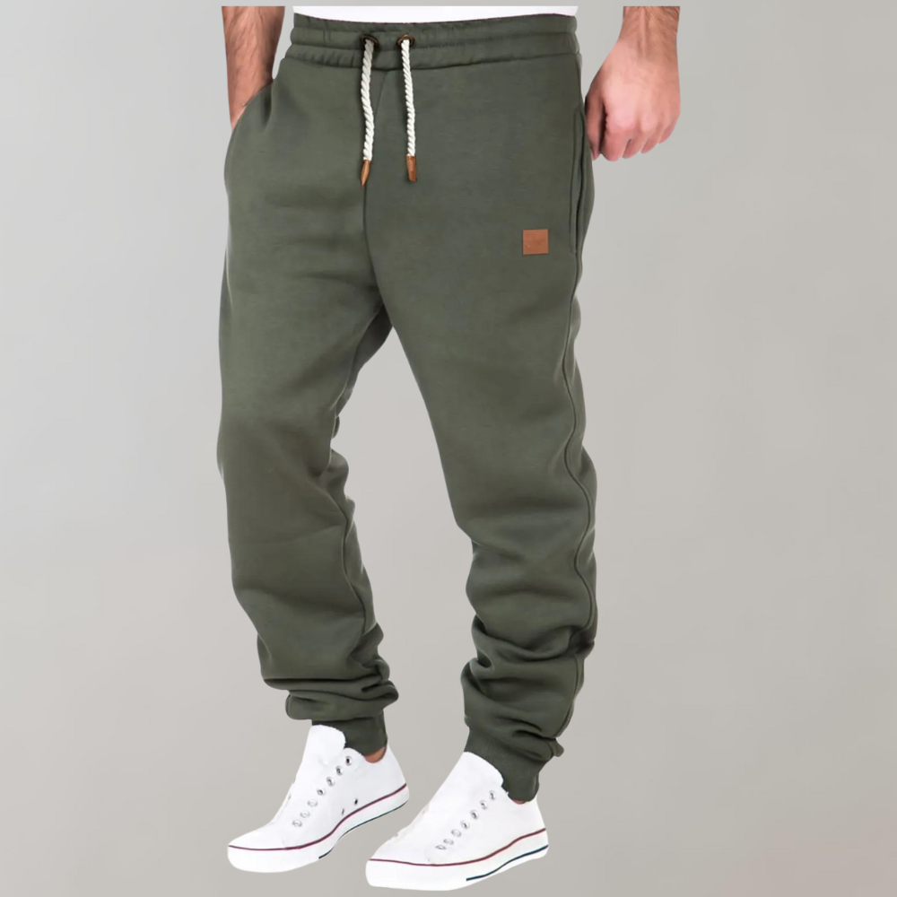 Olivgrüne Jogginghose mit Kordelzug und Beinbündchen, Hände in den Seitentaschen, dazu weiße Sneaker 3