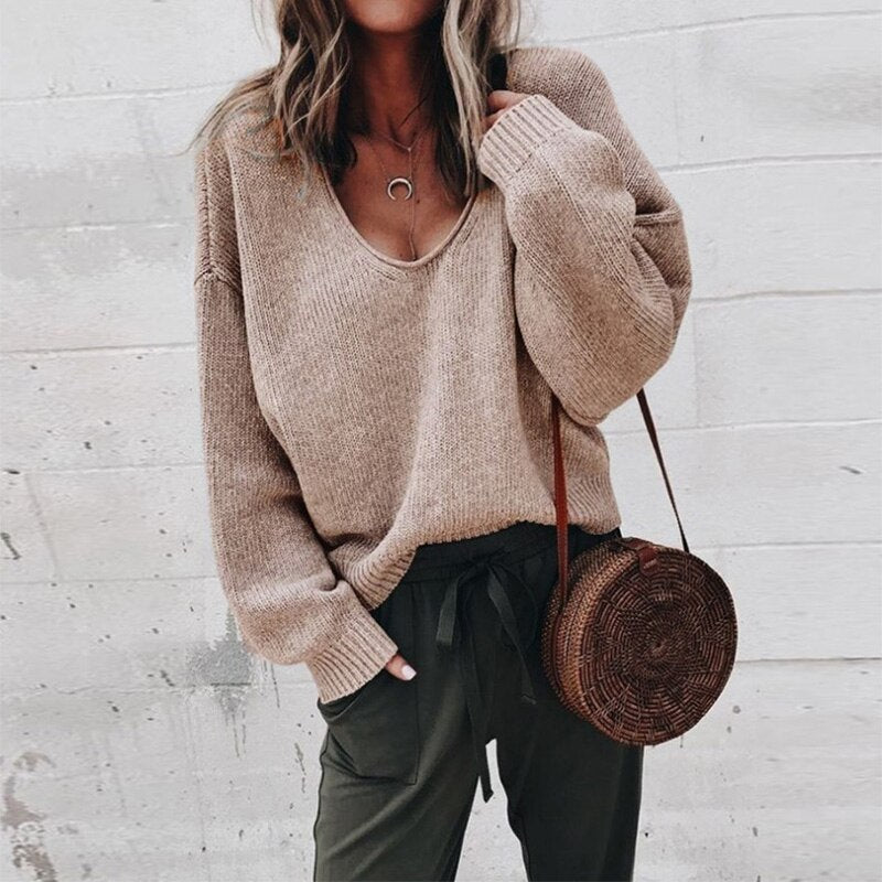 Frau in braunem V-Ausschnitt Strickpullover, lässig, mit runder Strohtasche, modisch.