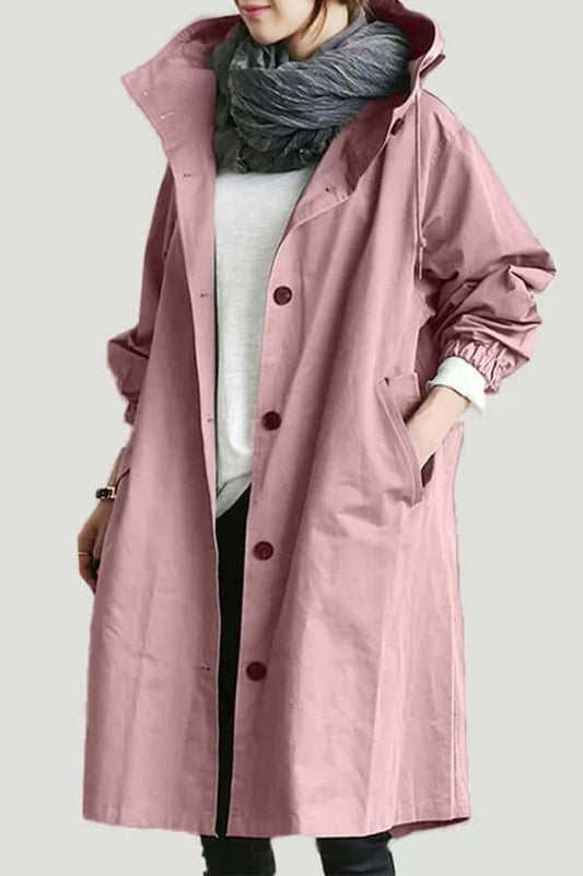 Langer Mantel in Rosa mit Knopfleiste, getragen mit grauem Schal, Hand in der Seitentasche 1