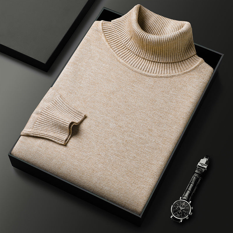 Beiger Rollkragenpullover gefaltet in einer schwarzen Geschenkbox, daneben eine Armbanduhr mit schwarzem Lederarmband; Rippkragen und Rippbündchen sichtbar. 1