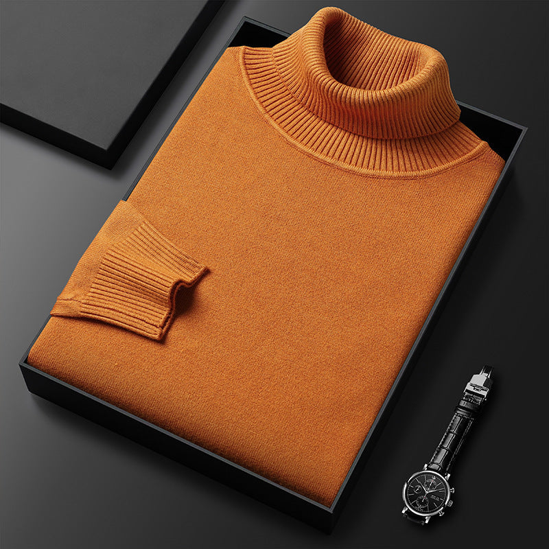 Orangebrauner Rollkragenpullover gefaltet in einer schwarzen Box, daneben eine Armbanduhr mit Lederarmband; Rippkragen und Rippbündchen am Ärmel sichtbar. 8