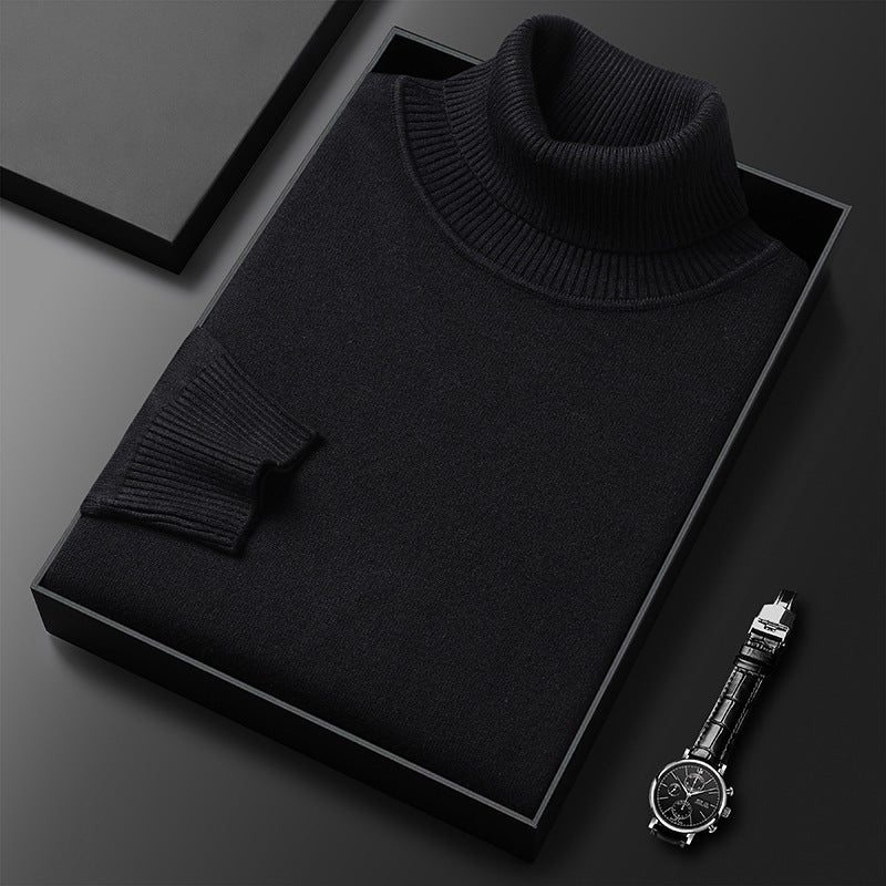 Schwarzer Rollkragenpullover gefaltet in einer schwarzen Box, daneben eine Armbanduhr mit Lederarmband; der gerippte Kragen und das Ärmelbündchen sind zu sehen.