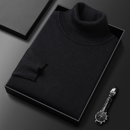 Schwarzer Rollkragenpullover gefaltet in einer schwarzen Box, daneben eine Armbanduhr mit Lederarmband; der gerippte Kragen und das Ärmelbündchen sind zu sehen.