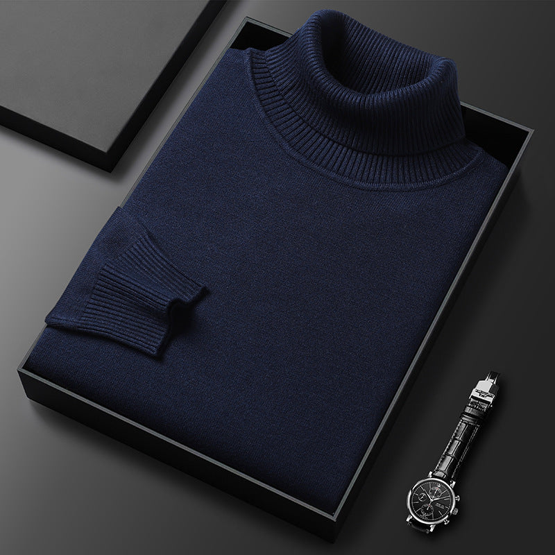 Dunkelblauer Rollkragenpullover gefaltet in einer schwarzen Box, daneben eine Armbanduhr mit Lederarmband; Rippkragen und Rippbündchen sichtbar. 4