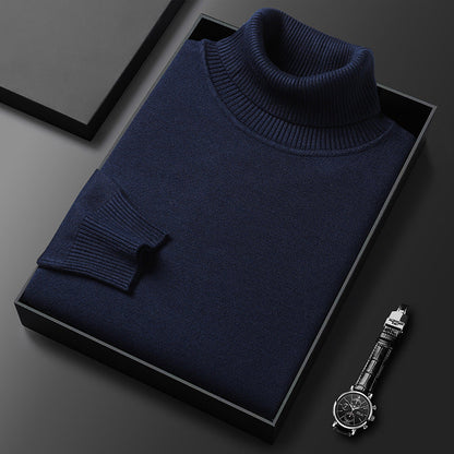 Dunkelblauer Rollkragenpullover gefaltet in einer schwarzen Box, daneben eine Armbanduhr mit Lederarmband; Rippkragen und Rippbündchen sichtbar. 4